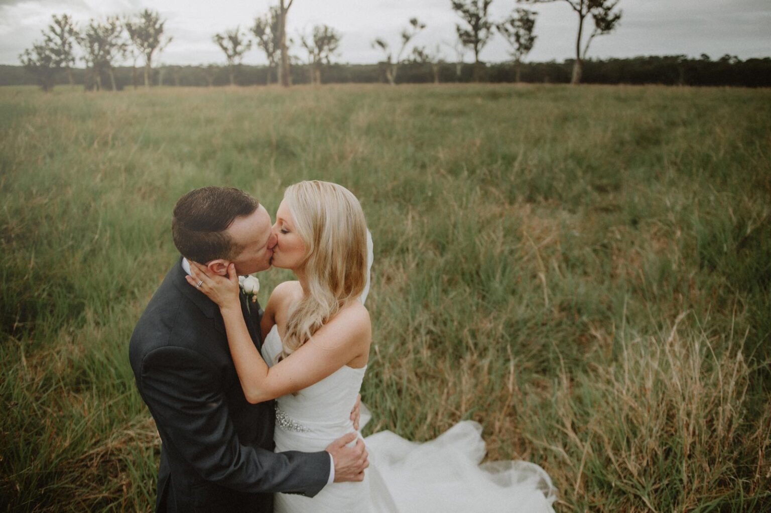 Sirromet Wedding - Couple kissing in field
