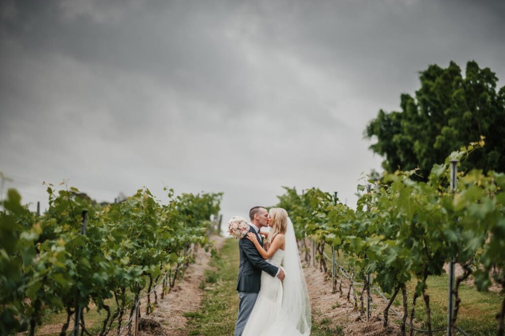 Sirromet Wedding - Couple kissing in vineyard